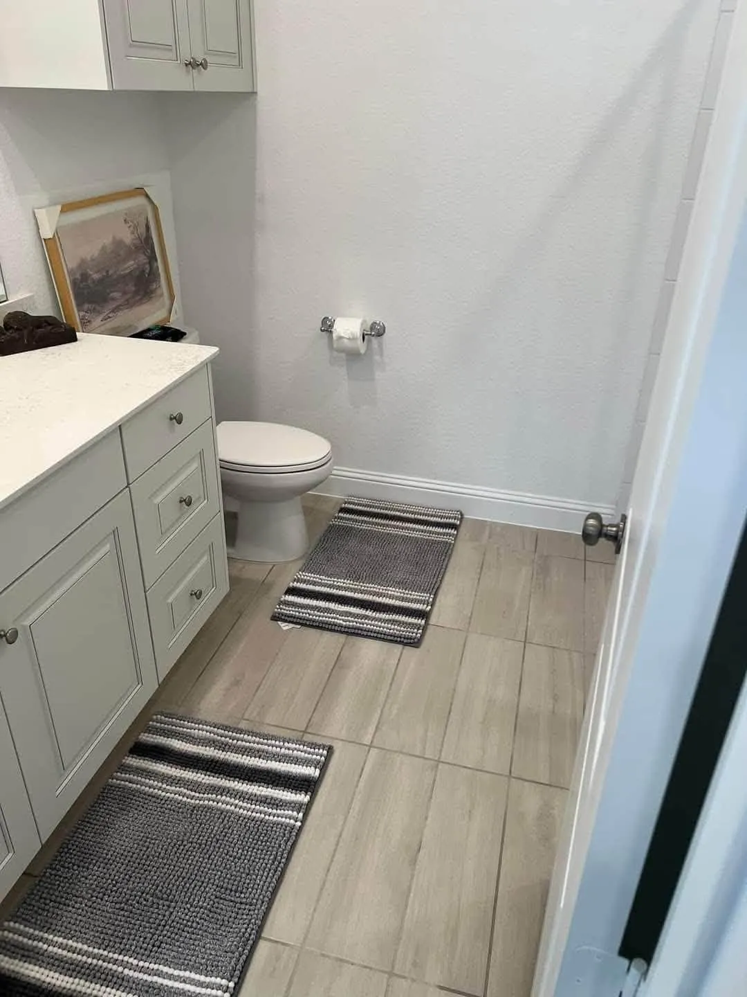 Clean bathroom with vanity, toilet and striped rugs