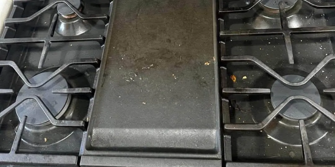 Gas range and griddle before cleaning with crumbs and residue