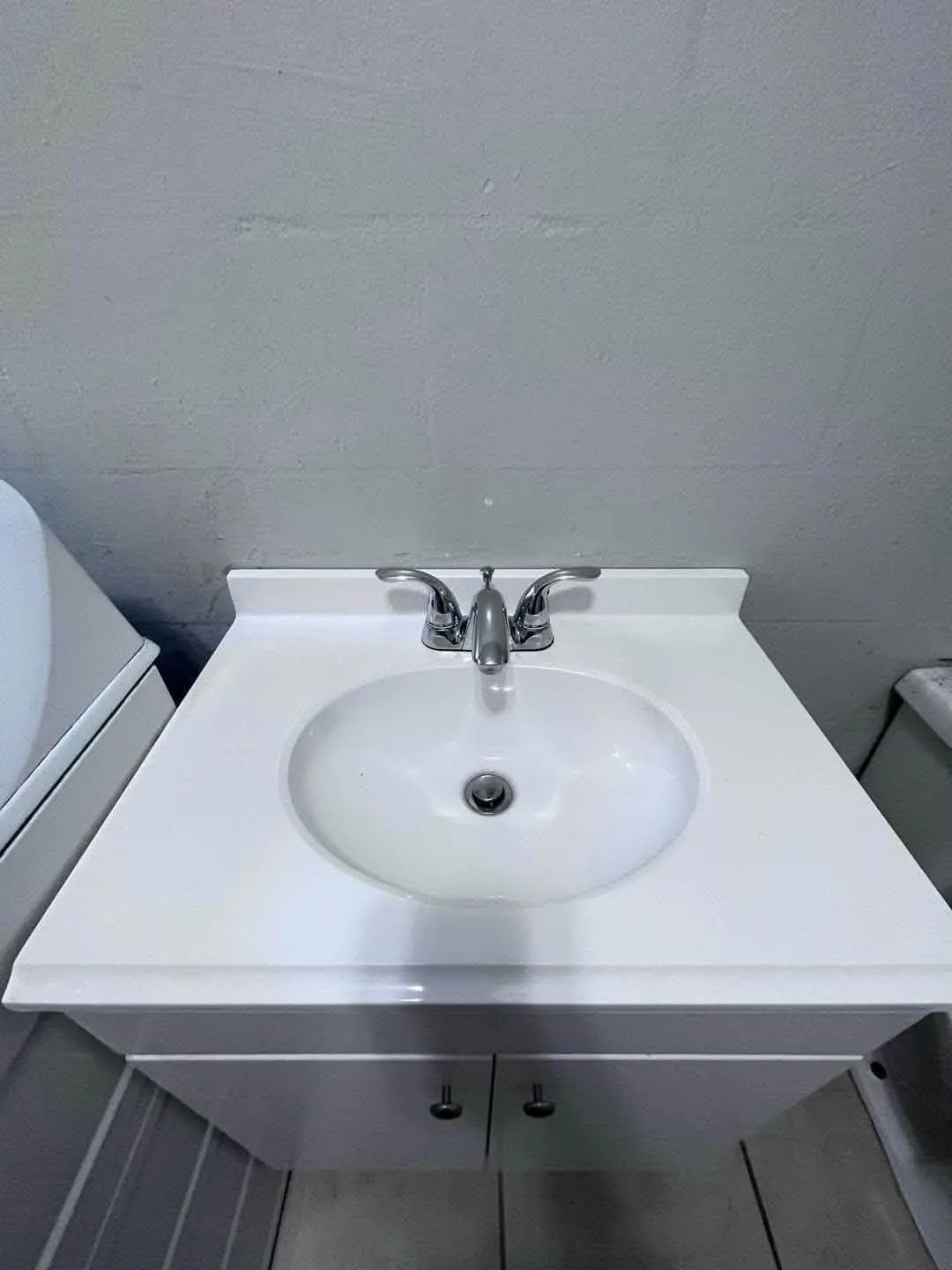 Bathroom sink after cleaning by NCS: bright white basin and polished chrome