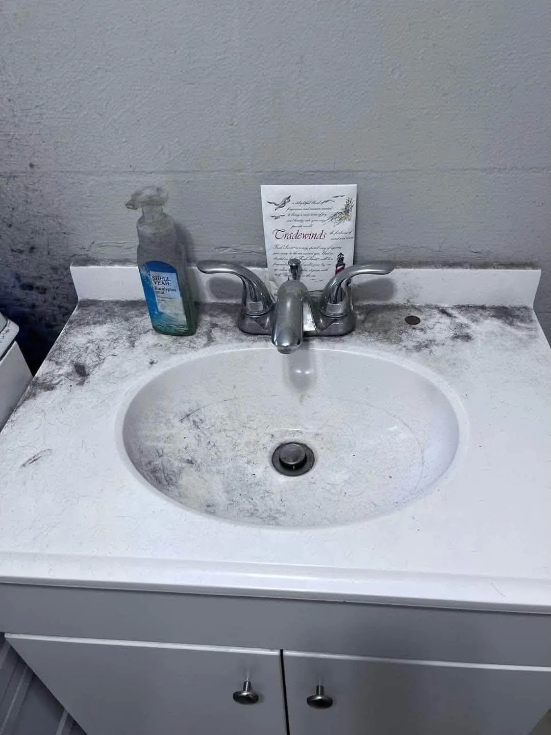The same bathroom sink before cleaning, covered in hair and grime